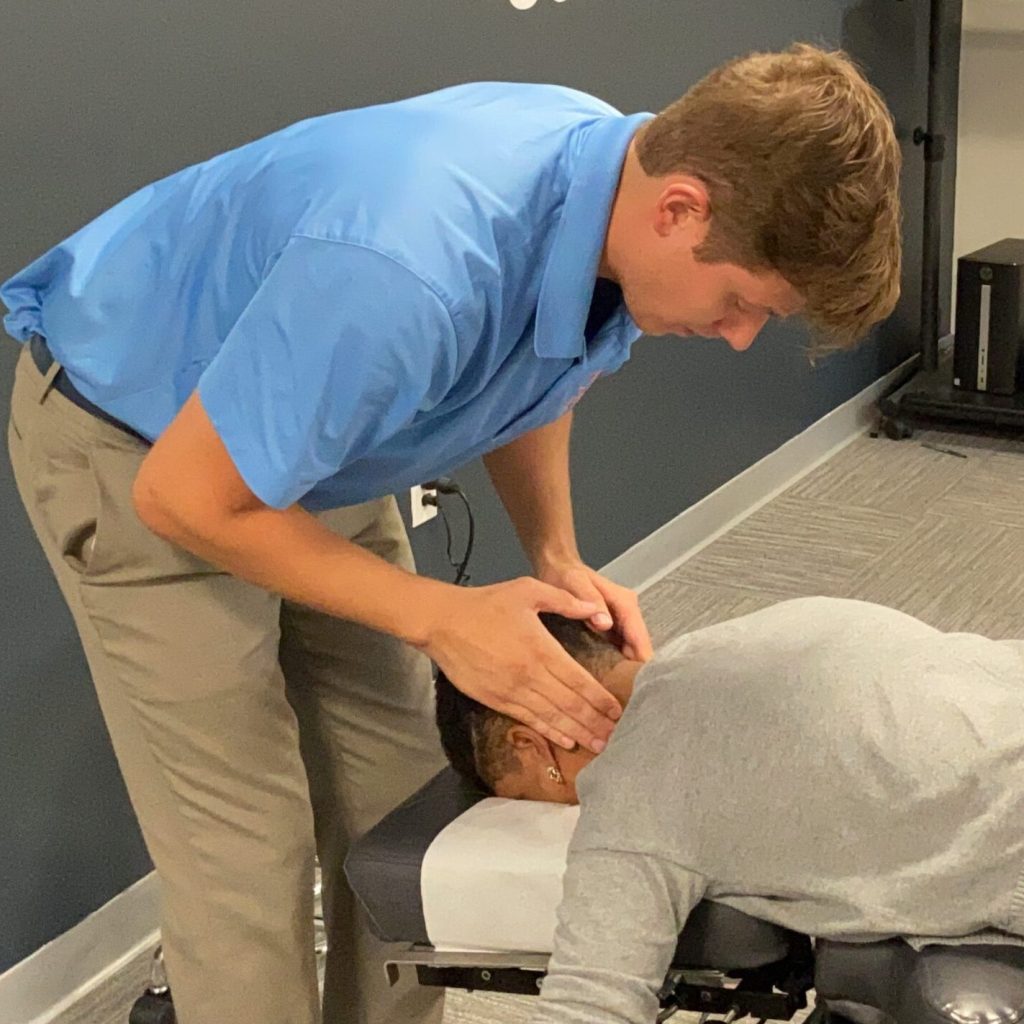 Chiropractor performing gentle neck adjustment on auto-injury patient.