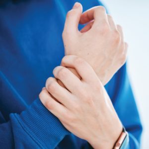 Person holding their wrist due to carpal tunnel related numbness and pain.