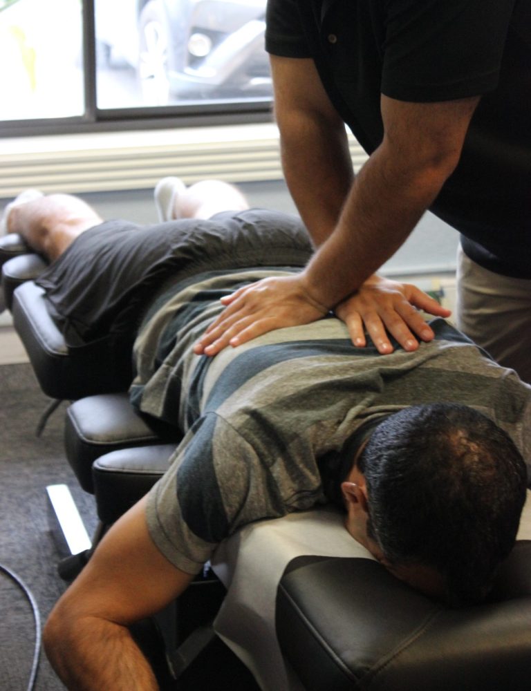 Chiropractor applying a hands on spinal adjustment, often paired with dry needling to relieve muscle tightness and improve mobility.
