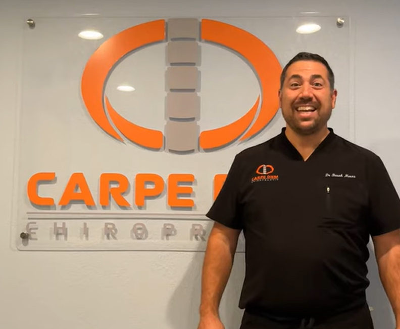 Clinic doctor standing in front of the Carpe Diem Chiropractic sign